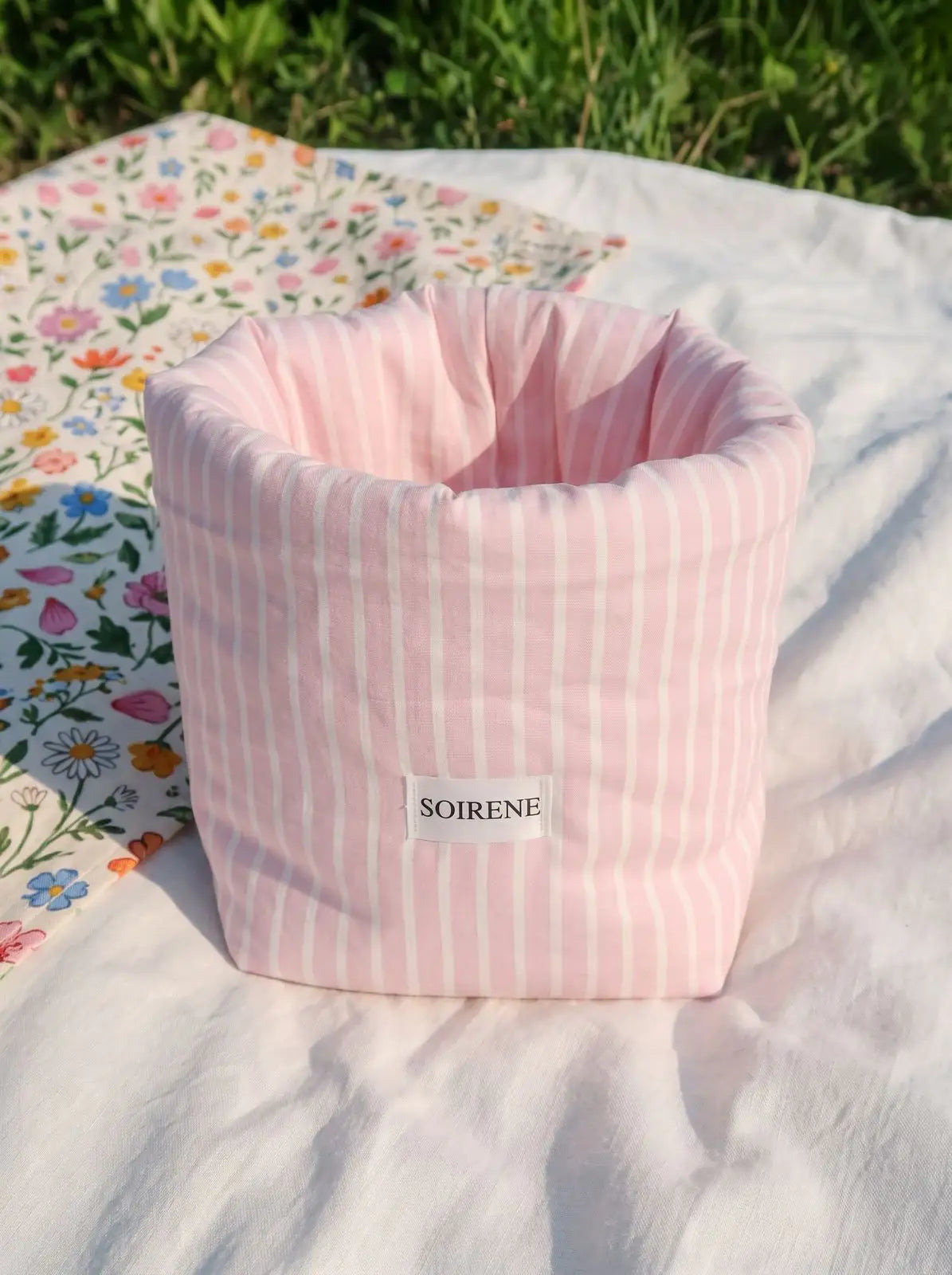 vanity bucket bubble rose à rayure blanche posé sur un drap dans un parc